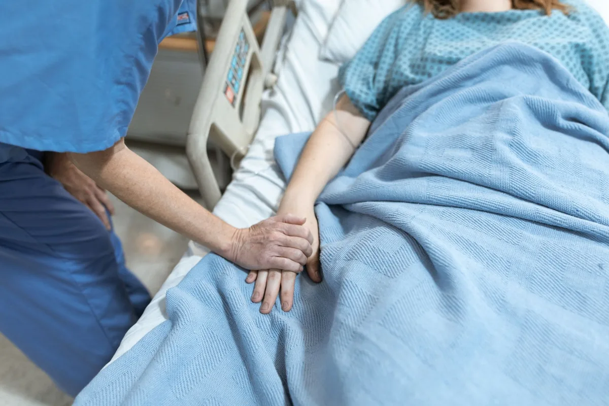 Sestra pečuje o pacientku na nemocničním lůžku